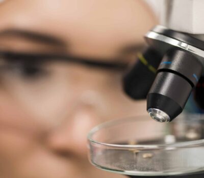 close up of microscope in the lab with female scientist close up of microscope in the lab with female scientist