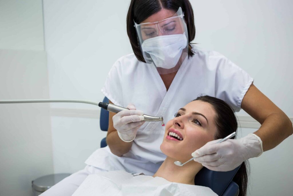 dentist examining female patient with tools
